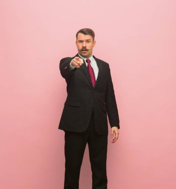 Pembe arka planda tek başına duran genç iş adamının portresi..