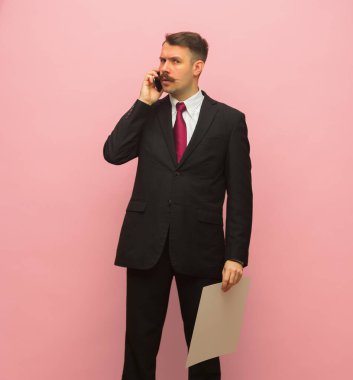 Telefonda konuşan genç iş adamının portresi pembe arka planda izole edilmiş..