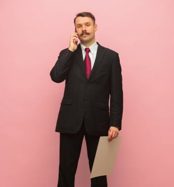 Telefonda konuşan genç iş adamının portresi pembe arka planda izole edilmiş..