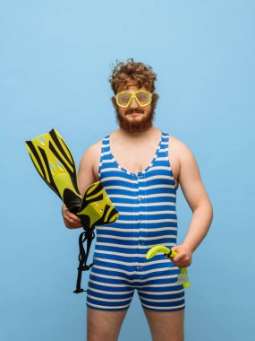 Mavi arka planda, mayolu ve gözlüklü komik kızıl saçlı adam..