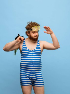 Mavi arka planda, mayolu ve gözlüklü komik kızıl saçlı adam..