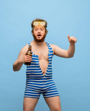 Mavi arka planda bira izole edilmiş mayo giymiş komik kızıl saçlı adam..