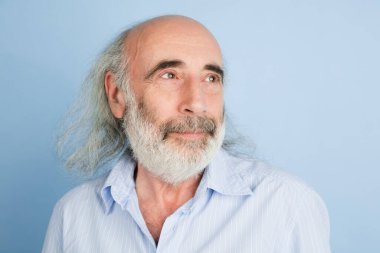Açık mavi arkaplan üzerinde izole edilmiş yaşlı gri saçlı adamın yakın plan portresi..
