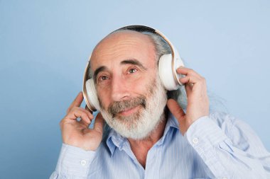 Yakın plan üst düzey gri saçlı, kulaklıklı adam açık arkaplanda izole edilmiş..