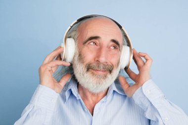 Yakın plan üst düzey gri saçlı, kulaklıklı adam açık arkaplanda izole edilmiş..