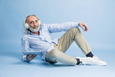 Tabletli yaşlı gri saçlı adam. Aygıt arka planda izole edilmiş..