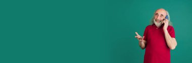 Akıllı telefonlu yaşlı gri saçlı adam yeşil arka planda izole edilmiş..
