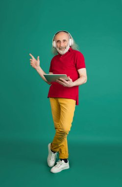 Yeşil arka planda izole edilmiş dizüstü bilgisayar kullanan yaşlı gri saçlı adam..