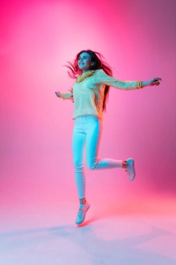 Pembe arka planda neon ışıkta izole edilmiş güzel bir kızın portresi.