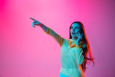 Telefonda konuşan güzel bir kız. Pembe arka planda, neon ışıkta izole edilmiş.