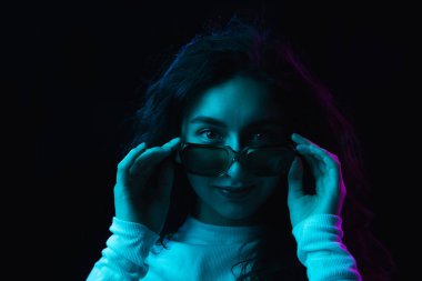 Yakın plan güzel kız, karanlık arka planda, neon ışıkta izole edilmiş.