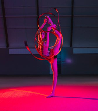 Zarif beyaz kız, jimnastikçi, renkli arka planda, neon ışıkta izole edilmiş.