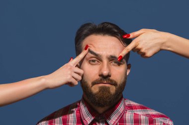 Mavi arka planda genç sakallı adama farklı duygular besleyen kadın eller.