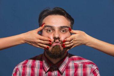 Mavi arka planda genç sakallı adama farklı duygular besleyen kadın eller.
