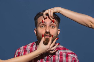 Mavi arka planda genç sakallı adama farklı duygular besleyen kadın eller.