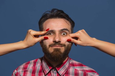 Mavi arka planda genç sakallı adama farklı duygular besleyen kadın eller.
