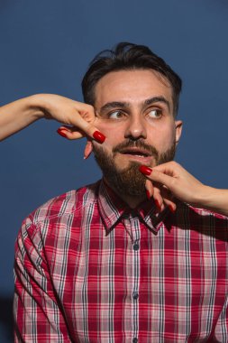 Mavi arka planda genç sakallı adama farklı duygular besleyen kadın eller.