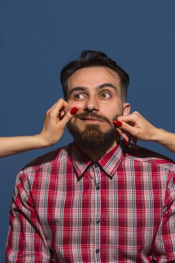 Mavi arka planda genç sakallı adama farklı duygular besleyen kadın eller.