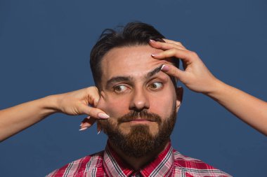 Mavi arka planda genç sakallı adama farklı duygular besleyen kadın eller.