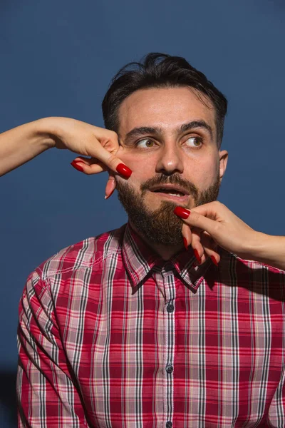 Mavi arka planda genç sakallı adama farklı duygular besleyen kadın eller.