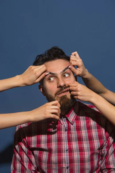 Dişi eller buruşuk sakallı genç adam mavi arka planda