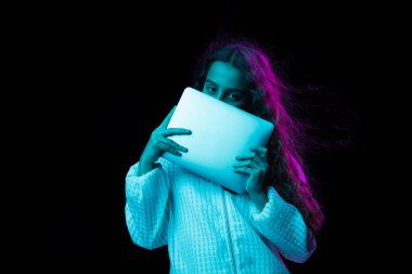 Tabletli genç ve güzel bir kız karanlık arka planda neon ışıkta izole edilmiş.