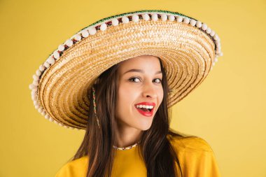 Sombrero 'daki genç, güzel, mutlu kız sarı arka planda izole edilmiş..