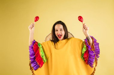 Parlak elbiseli güzel bir kız ve sarı arka planda izole edilmiş bir sombrero.