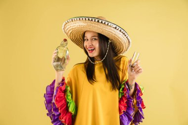 Parlak elbiseli güzel bir kız ve sarı arka planda izole edilmiş bir sombrero.