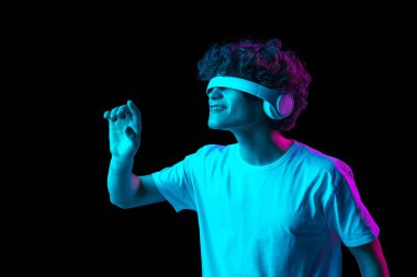 Kulaklıklı genç adamın portresi, karanlık arka planda, neon ışıkta izole edilmiş.