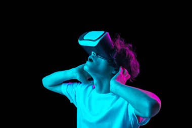 VR kulaklık kullanan genç adam karanlık arka planda, neon ışıkta izole edilmiş.