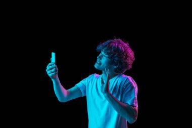 Kafkasyalı genç adam telefonda konuşuyor. Karanlık arka planda, neon ışıkta izole edilmiş.