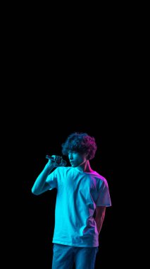 Genç beyaz adamın portresi neon arka planda izole bir şekilde şarkı söylüyor.