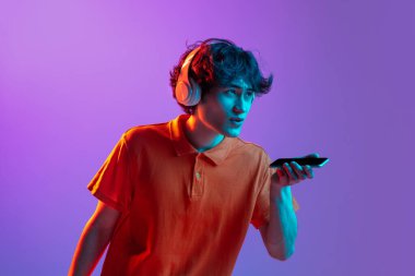 Telefon ekranı gösteren genç adam neon renkli arka planda izole edildi