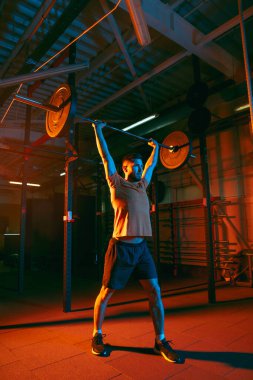 Genç atletik adam, beden eğitimi hocası karışık neon ışıkta..