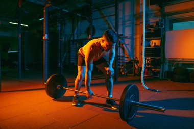 Genç atletik adam, beden eğitimi hocası karışık neon ışıkta..