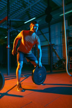 Genç atletik adam, beden eğitimi hocası karışık neon ışıkta..