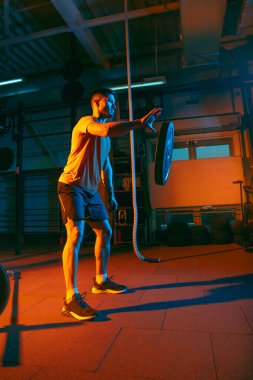 Genç atletik adam, beden eğitimi hocası karışık neon ışıkta..