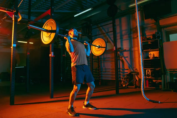 Genç atletik adam, beden eğitimi hocası karışık neon ışıkta..