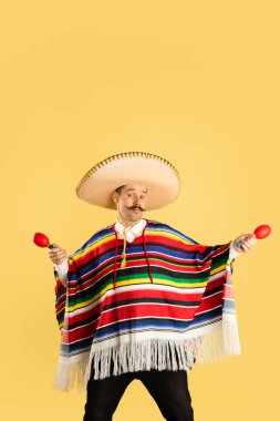 Sombrero ve parlak pançolu mutlu adam sarı arka planda izole edilmiş.