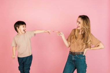 Genç bir kadın ve küçük bir çocuk, anne ve oğlu pembe arka planda izole edilmiş..