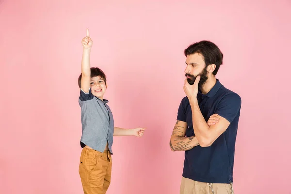 Két ember, férfi és kisfiú, apa és fia elszigetelve rózsaszín háttér. — Stock Fotó