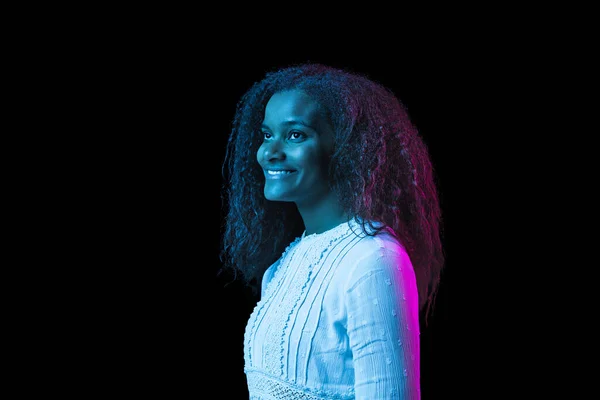 Young beautiful African-American girl isolated on dark background in neon light — Stock Photo, Image