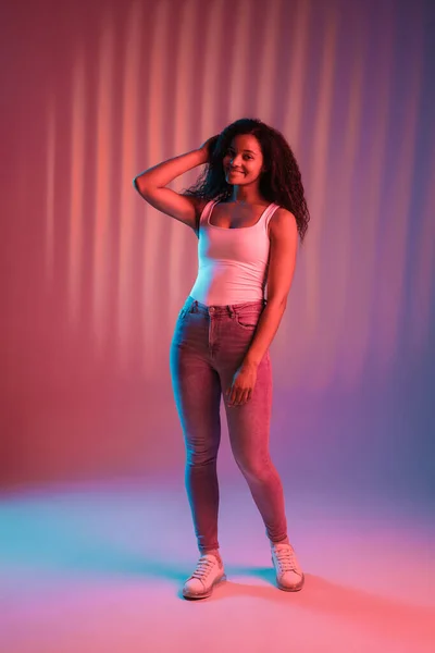 Young beautiful happy African-American girl isolated on pink background in neon. — Stock Photo, Image