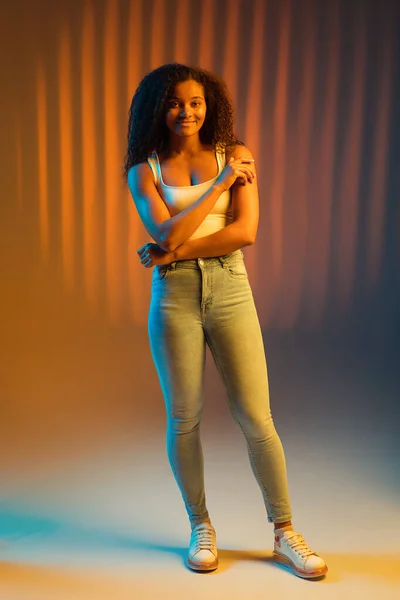 Beautiful happy African-American girl isolated on colored background in neon. — Stock Photo, Image