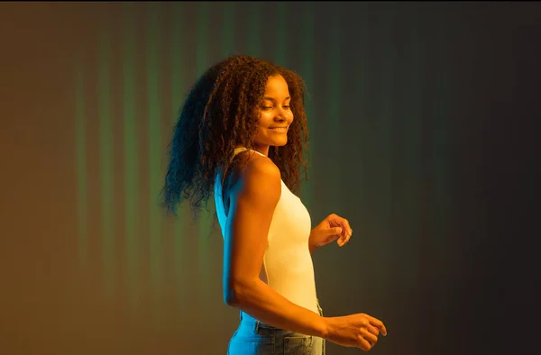 Young happy African-American girl isolated on colored background in neon. — Stock Photo, Image