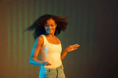 Genç mutlu Afro-Amerikalı kız neon renkli arka planda izole edilmiş..