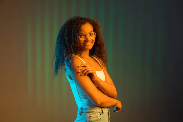 Menina afro-americana feliz bonita isolada em fundo colorido em néon. — Fotografia de Stock