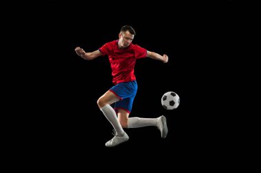 Kafkasyalı genç futbolcu siyah arka planda tek başına antrenman yapıyor.