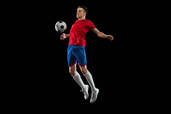 Молодий кавказький футболіст практикує ізольований на чорному фоні. — стокове фото